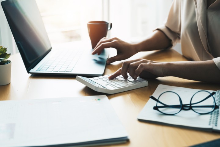 A procurement professional sits at a desk and calculates prices