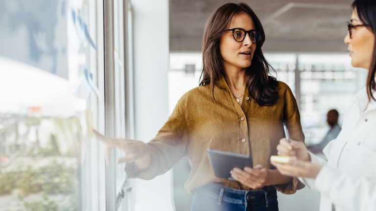 Two women from the Legal Team discuss compliance matters at the office