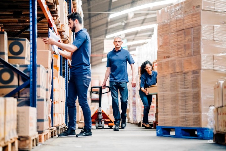 Three people sort warehouse consignment
