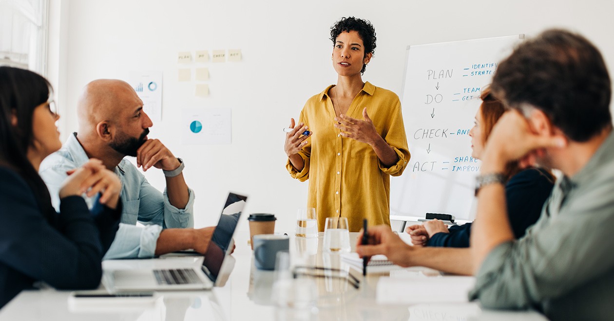 Procurement specialist speaking in front of other procurement professionals in a meeting room