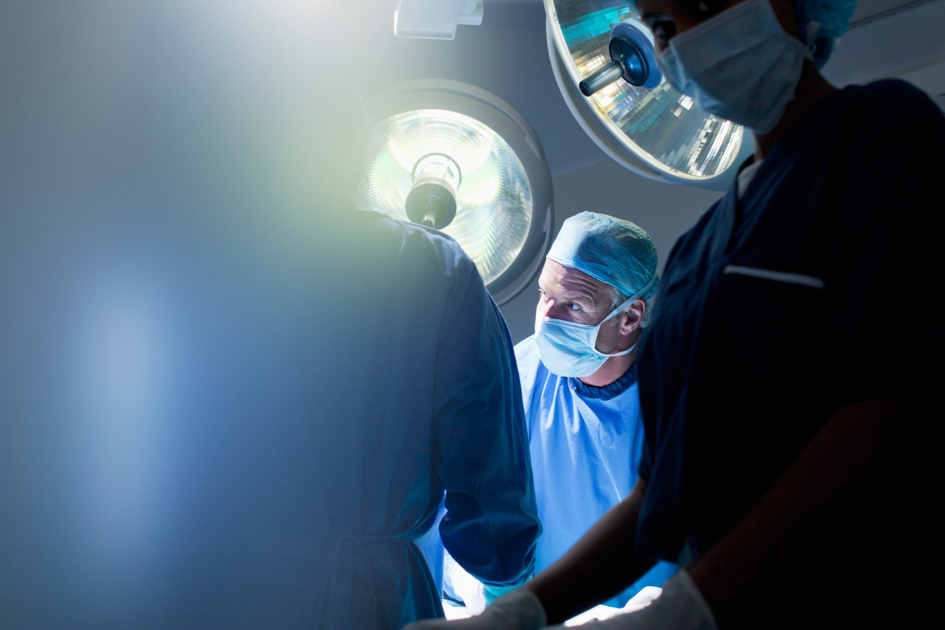 Picture of a male surgeon in a operating room, performing a surgery