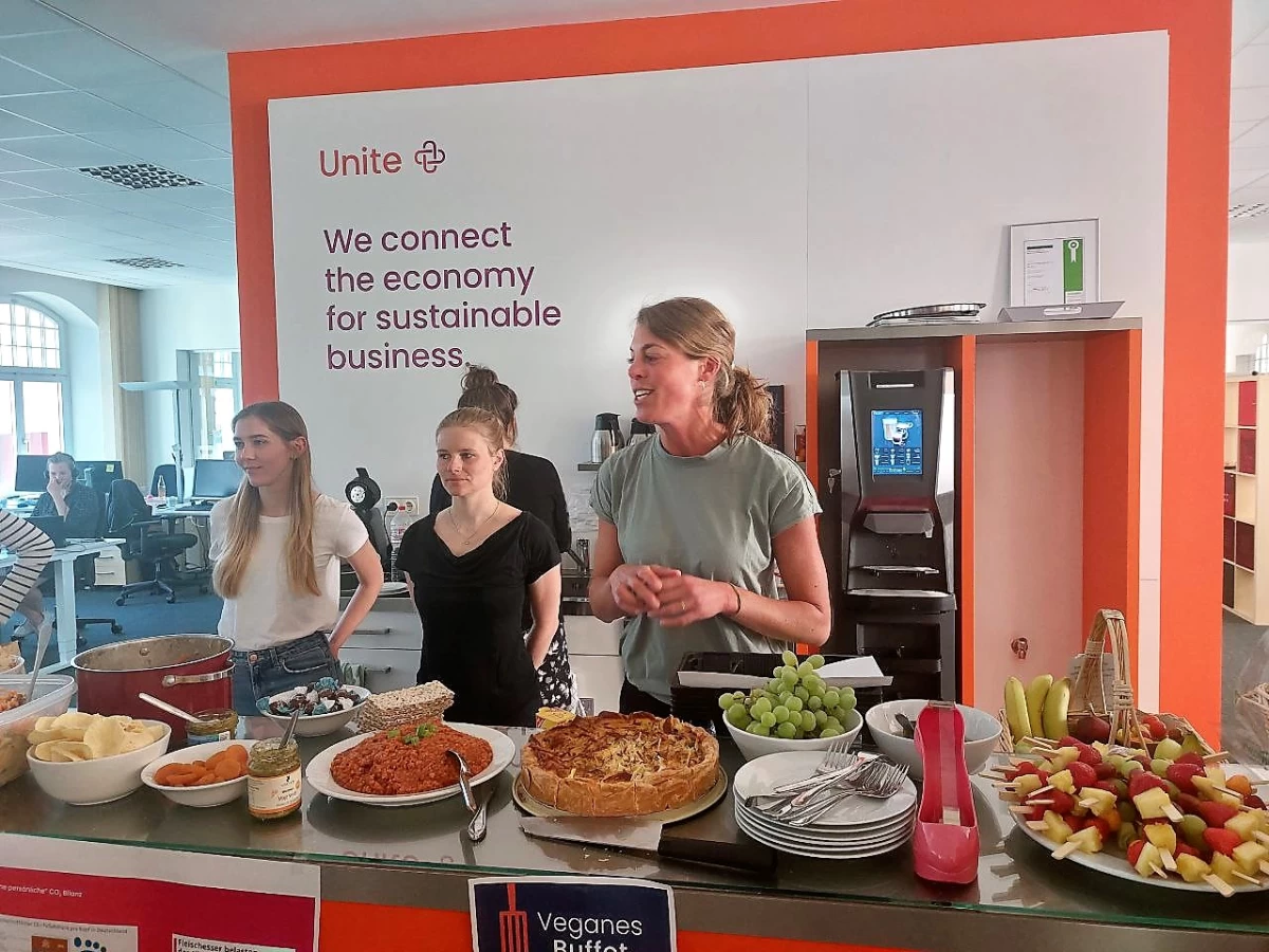 Trois collaboratrices présentant les divers plats du buffet végan dans les locaux de la société