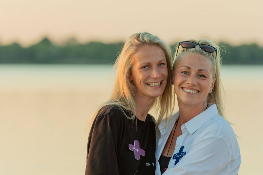Twee vrouwen dicht bij elkaar glimlachen naar de camera aan het water