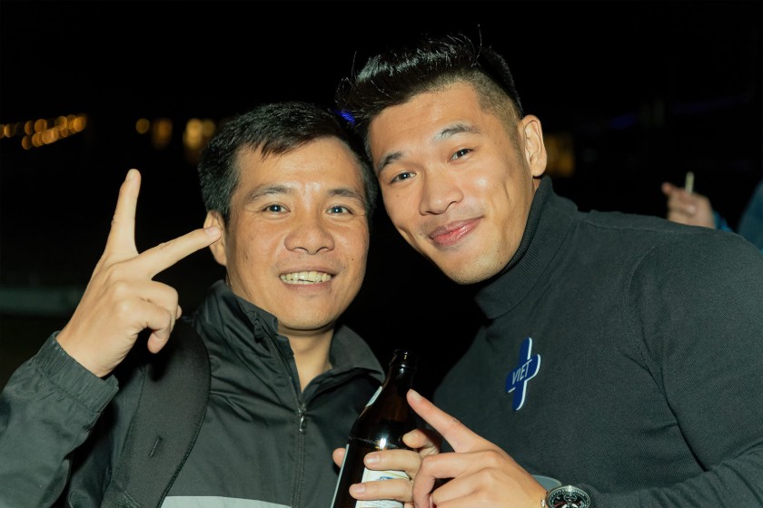 Twee mannen uit Vietnam lachen naar de camera op het zomerfeest ’s avonds