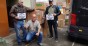 Three men in front of donation boxes