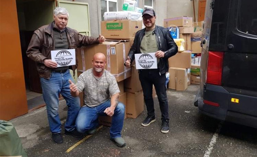 Three men in front of donation boxes