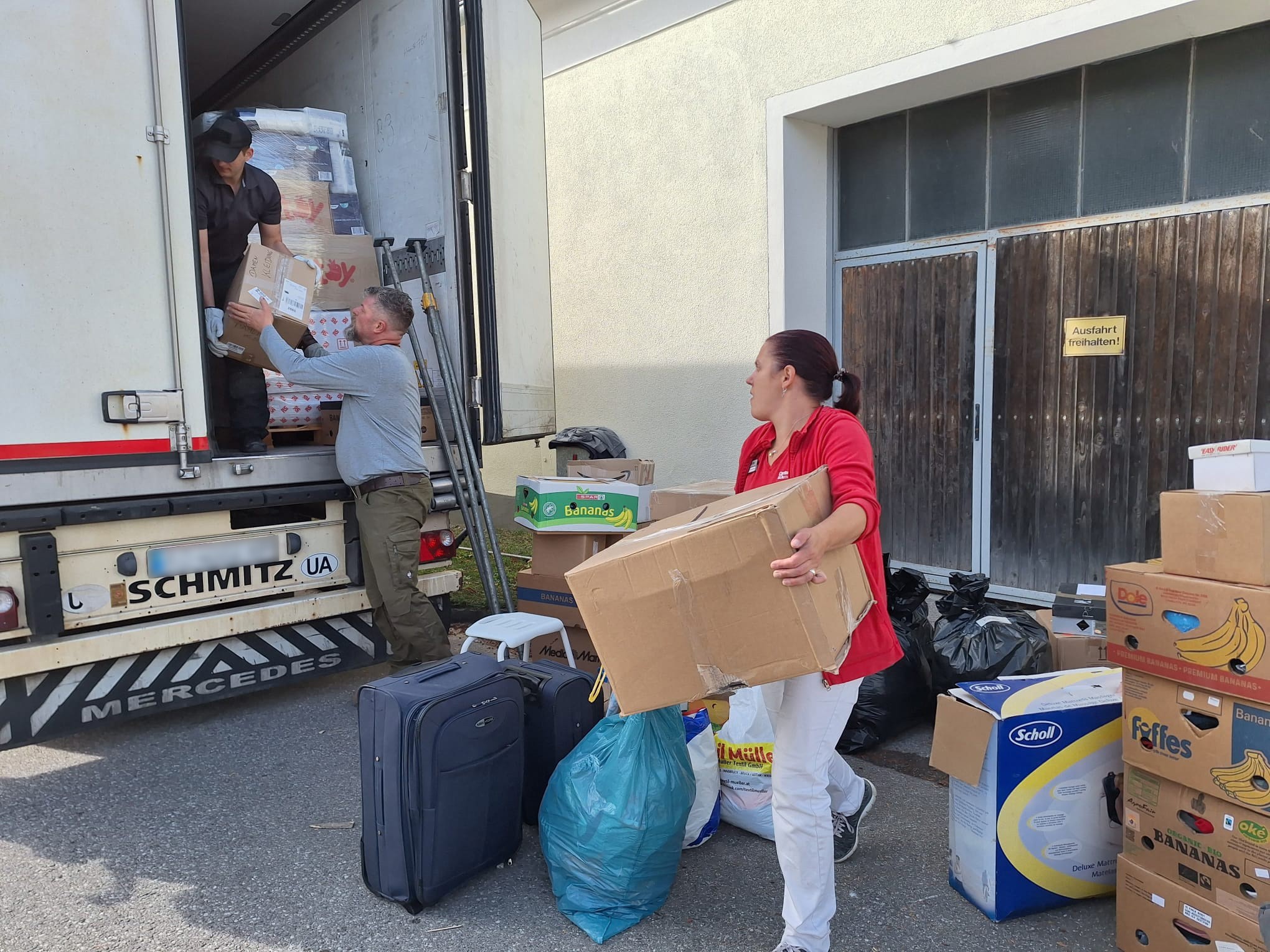 Menschen packen einen LKW mit Kartons