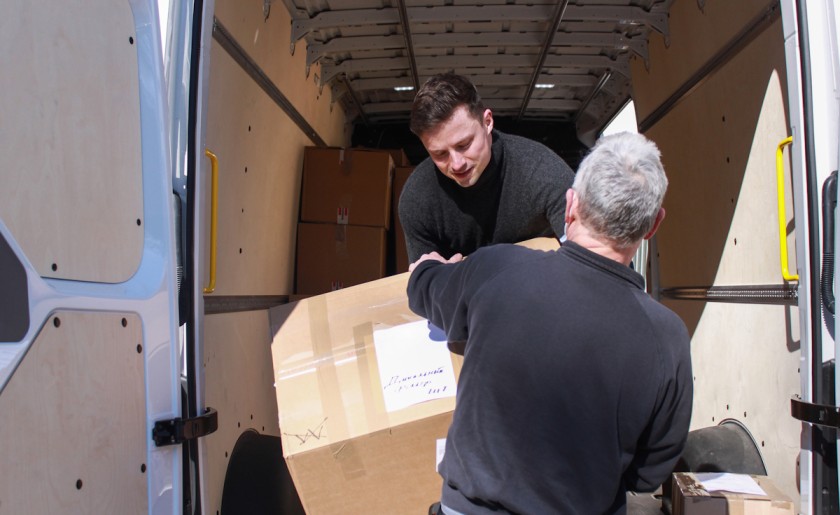 Zwei Männer laden einen Karton in einen Transporter