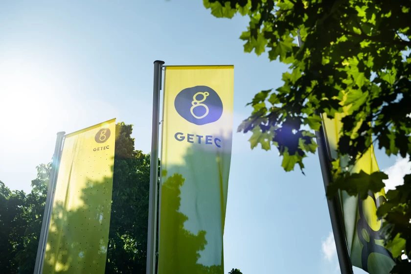 GETEC company flags next to some trees with the sky in the background