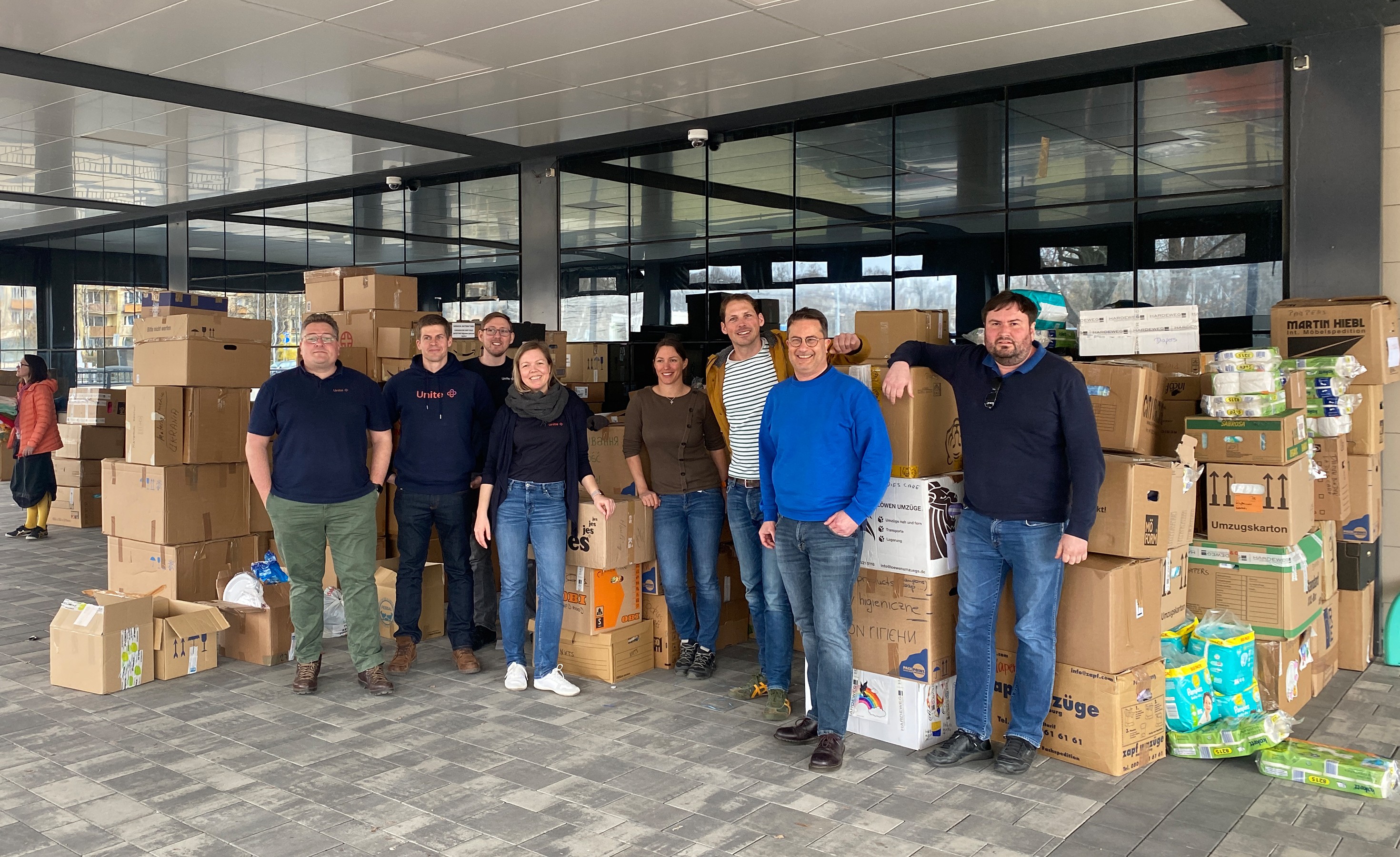 Unitees vom Plattformmanagement stehen vor gepackten Spendenkartons