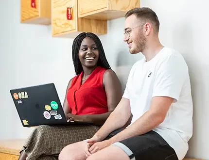 Two Unitees look at a laptop