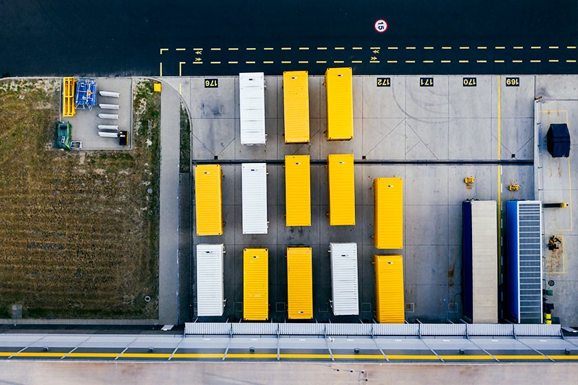 The picture shows thirteen containers in yellow and white on a storage yard from a bird's eye view
