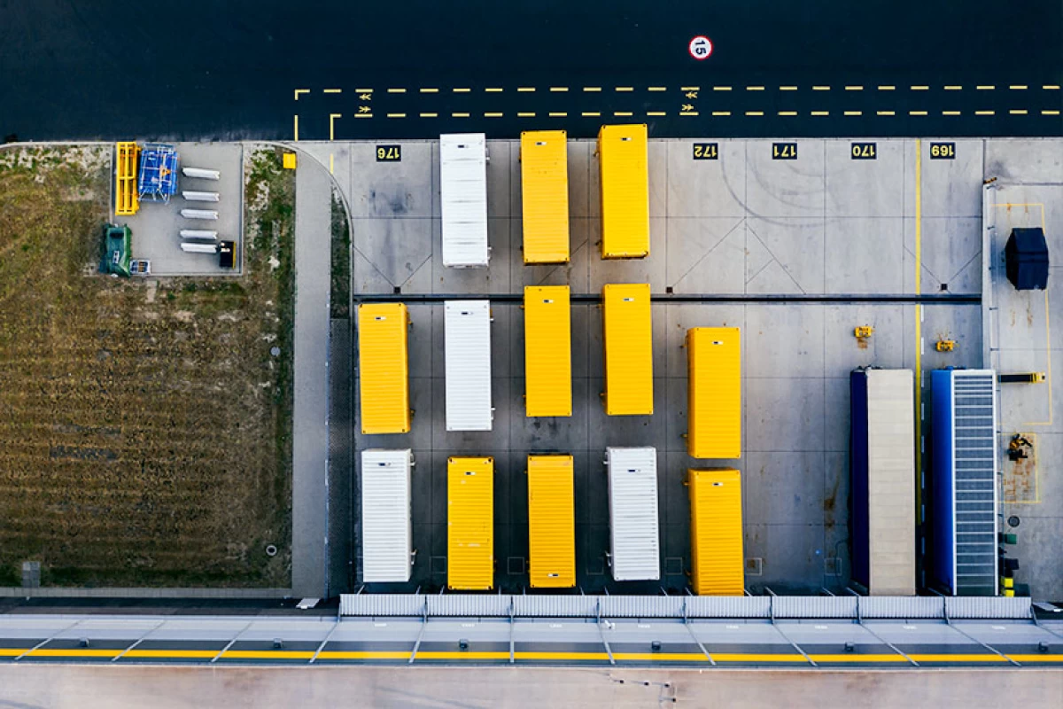 Thirteen containers in yellow and white on a storage yard from a bird’s eye view